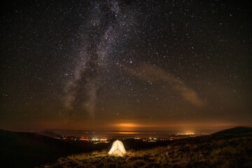 Milky way and solo wildcamping tent on grassy summit, Nanttle, Wales, UK.