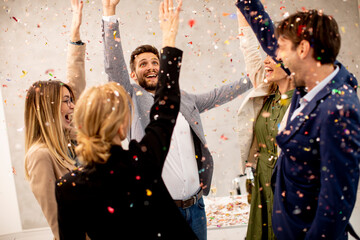 Group of business people celebrating and toasting with confetti falling in the office - obrazy, fototapety, plakaty