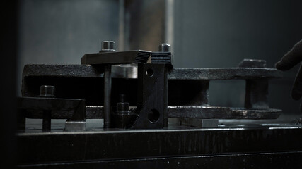 Plakat Worker installs a metal workpiece in the machine