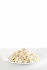 Homemade cheese on a white plate. Cheese with raisins. Isolate.