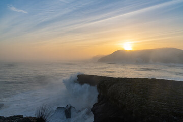 Obraz premium huge storm surge ocean waves crashing onto shore and cliffs at sunrise