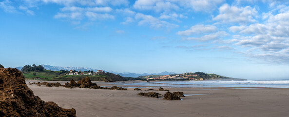 sandy beach panorama landscape with seaside village in the hills behind