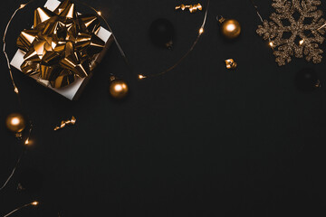 Xmas wreath. White gift with golden bow, gold balls and sparkling lights garland in Christmas...