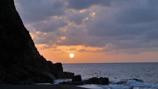 Sunset over the sea with clouds and a rocky cliff Martinique anse levrier beach 