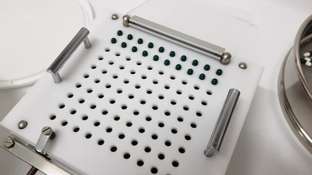 Capsules encapsulation equipment, white and green pills. Medical lab concept