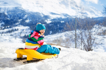 Fototapeta na wymiar Girl on sled ride. Child sledding. Kid on sledge