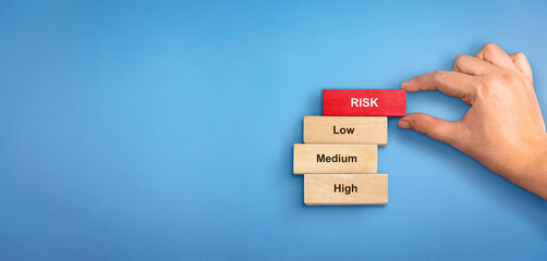 Risk concept with text high, medium and low. Hand holding wooden block with text Risk. Risk Management concept, Risk meter.