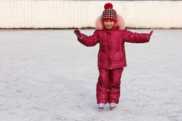 Happy girl rides in the winter on the ice rink on skates. Figure skating training. Winter sports...