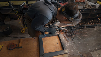 A man in gloves cuts metal with a circular saw, a lot of sparks. The working process