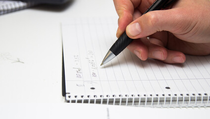 The student solves mathematical formulas. Man writes with a pen in a notebook.