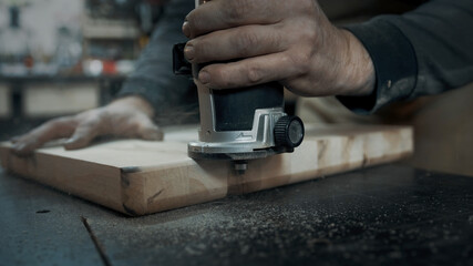 A carpenter mills the edges of a wood loft chair.