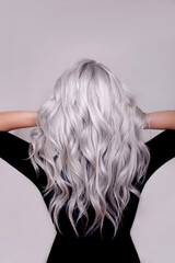 Female back with long, curly, ombre, blonde hair, on grey background