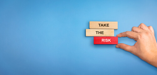 Risk concept. Wooden blocks with text Take the Risk. Hand holding risk wooden red block.