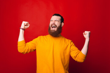 Photo of an excited man screaming of happiness with both hands up .