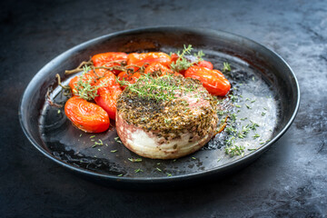 Traditioneller italienischer Ricotta al forno Kuchen mit gegrillten Tomaten und Kräuter angeboten als close-up auf einem rustikalen Teller 