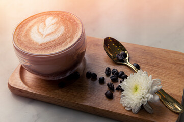 Hot latte art on wooden plate with sunlight morning