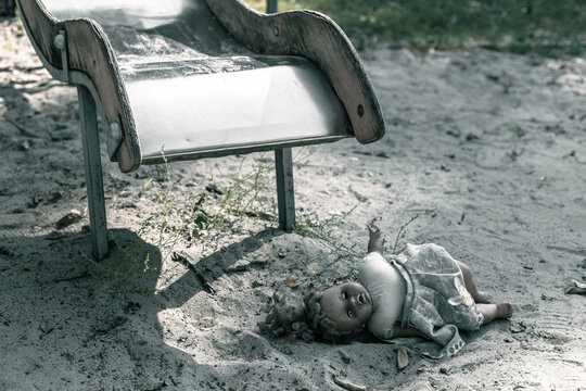 Creepy doll lies on an old abandoned playground. A dirty ugly doll lies on the sand