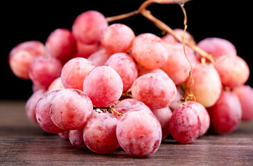 A bunch of red grapes on a wooden table.