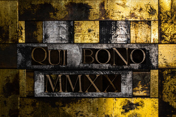 Qui Bono MMXX text message on vintage textured gold silver and copper background