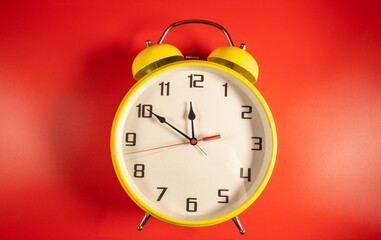 Yellow Retro style alarm clock on red background.