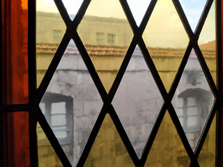 Watching out a stained glass window. Looking at the view of an old building