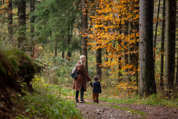 Fototapeta premium mother and son walk through the forest in autumn