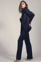 Fashion minimalist portrait of brunette female model on grey background. stylish clothing, black  classic style concept