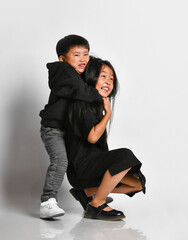 Fototapeta premium little boy hugging his older sister from behind and smiling looking at the camera