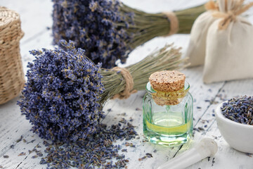 Lavender essential oil bottle, mortar, sachet bags and bouquets of dried lavender flowers.