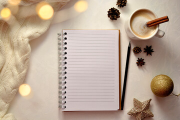 Winter creative cosy flat lay. Empty open notebook, coffee cup, winter decorations and bokeh lights.