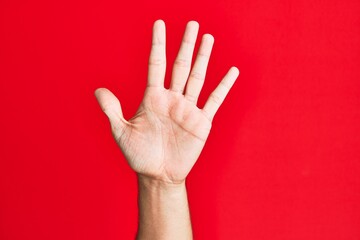 Arm of caucasian white young man over red isolated background counting number 5 showing five fingers