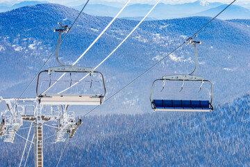Armchair lift for ski resort on background of mountains and blue sky, sunny day