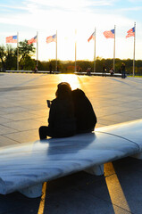 Silhouettes and U.S. national flags at the Washington Monument grounds during sunset - Washington...
