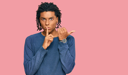 Young african american man wearing casual winter sweater asking to be quiet with finger on lips pointing with hand to the side. silence and secret concept.