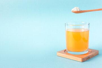 Spoon of protein or collagen and orange juice. Food supplement concept. Natural beauty and health supplement