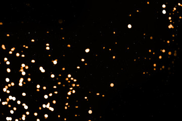 Splash of golden sparkles on black background. Bokeh lights. Sparkling texture