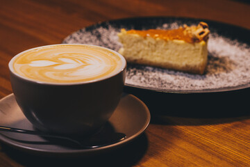 Cup of latte with curd cheesecake on dark wooden background