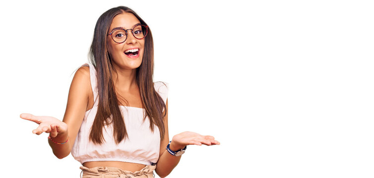 Young hispanic woman wearing casual clothes and glasses smiling cheerful offering hands giving assistance and acceptance.