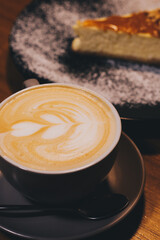 Cup of latte with curd cheesecake on dark wooden background