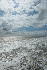 Fototapeta premium Foaming wild sea with a beautiful cloudy sky directly above it. Connect together.