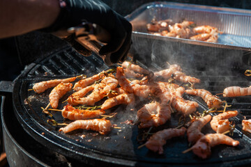 A professional cook prepares shrimps on the grill outdoor, food or catering concept