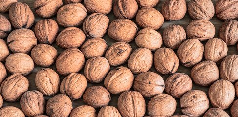 Whole brown walnuts with shell. Autumn food background.