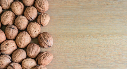 Border of whole walnuts on wooden background.