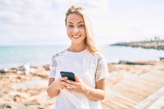 Young caucasian girl smiling happy using smartphone at street of city.