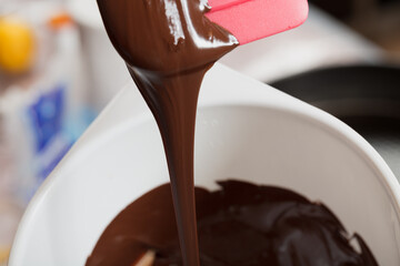 Pouring fresh chocolate cream on a white bowl.