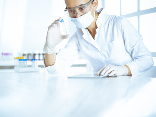 Female laboratory assistant analyzing a blood sample at hospital. Medicine, health care and researching concept
