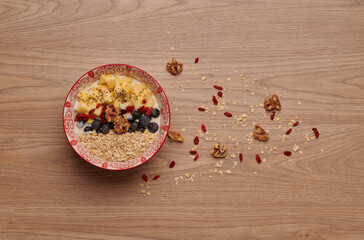 Healthy snacks in bowl: yoghurt, oat flakes, fruit, chia and goji seeds.