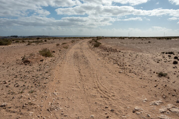 Dirt road with Atlantic Ocean in the background. Barlovento desert area, Fuerteventura, Canary Islands. 