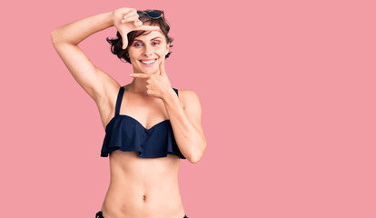 Naklejka premium Beautiful young woman with short hair wearing bikini smiling making frame with hands and fingers with happy face. creativity and photography concept.