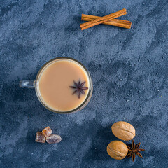 Glass cup of traditional indian masala tea on dark background. Winter hot drink cocoa with cinnamon. Copy space for text